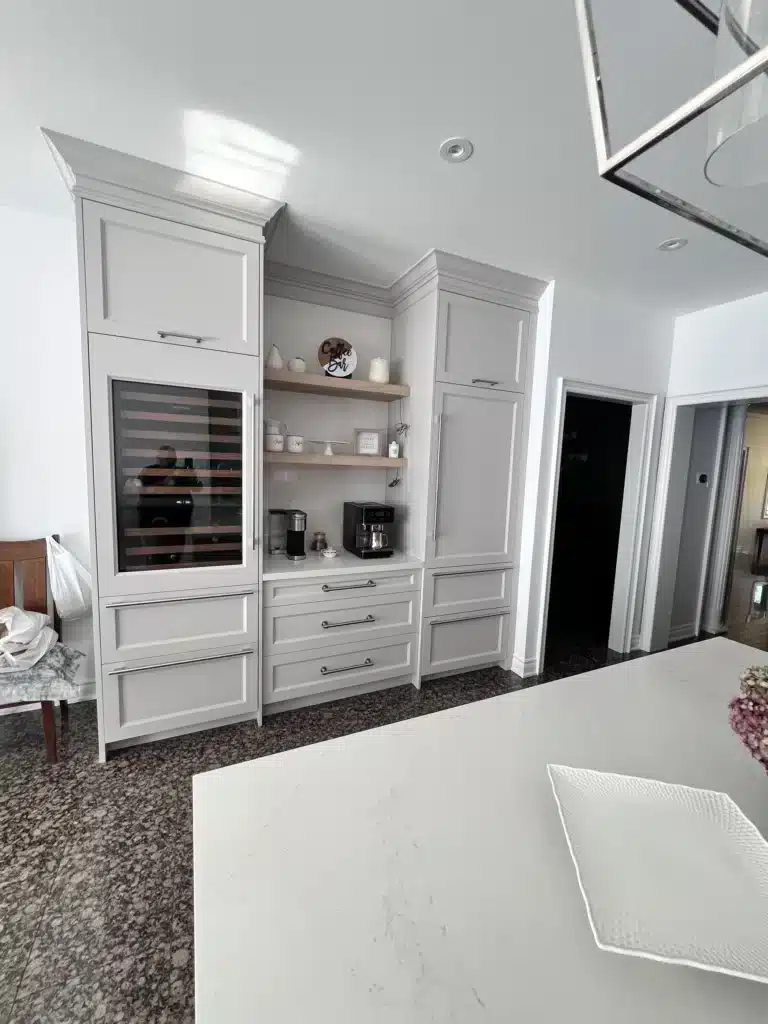 Coffee bar cabinets in an Ontario home: a built-in beverage station with a glass-front wine fridge, open walnut shelving and a drawer bank.