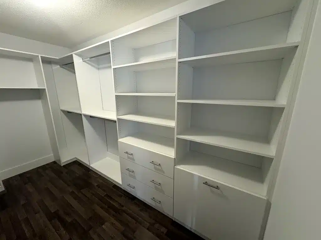 Custom closet design in an Ontario home: a walk-in with a deep open shelf tower beside a drawer bank and corner hanging.