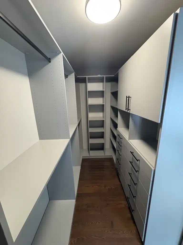 Custom closet design in an Ontario home: a two-tone walk-in with a long drawer bank, upper cabinets and high-low hanging down both walls.