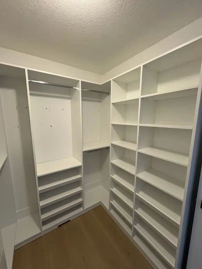 Custom closets in an Ontario home: a walk-in with a full-height angled shoe wall opposite long hanging and open shelving.