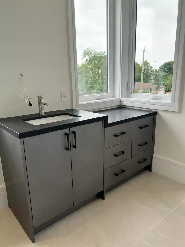 Laundry room cabinets in an Ontario home: dark Contemporary cabinetry with an undermount sink base and a six-drawer bank under a stone top.