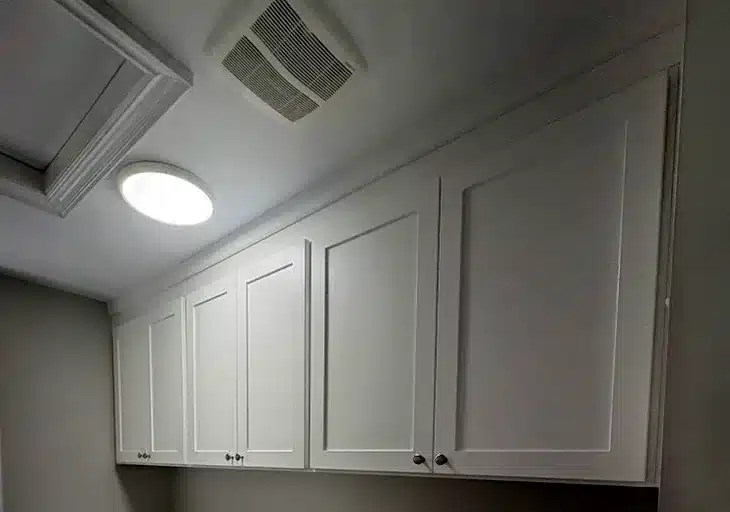 Laundry room cabinets in an Ontario home: a run of white shaker upper cabinets built above the washer and dryer.