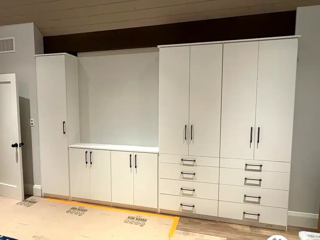 Mudroom cabinets in an Ontario home: a white mudroom run with a bench seat, closed cubby storage and tall flanking cabinets.