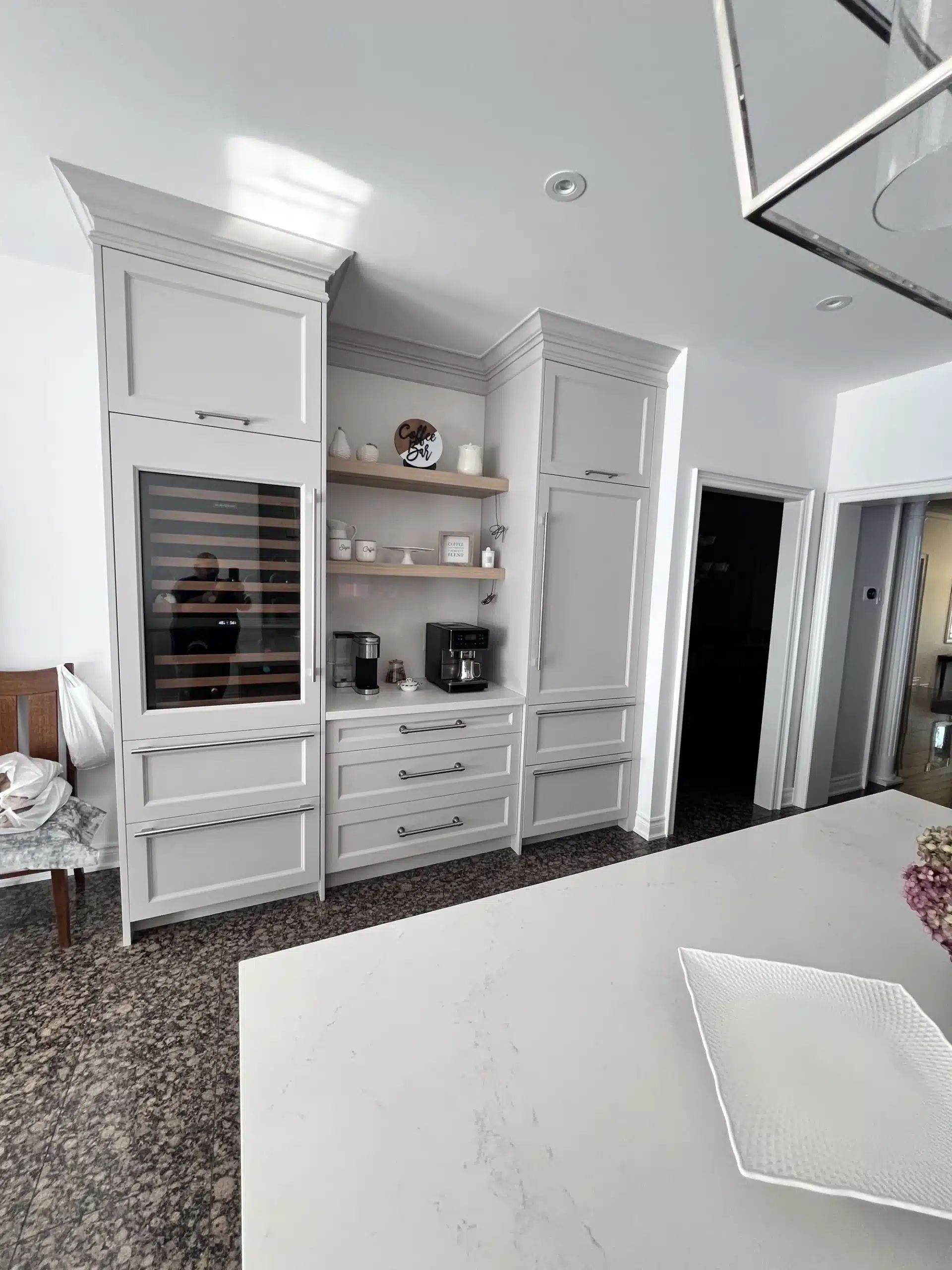 Small kitchen storage in an Ontario home: a built-in beverage station with a glass-front wine fridge, open walnut shelving and a drawer bank.