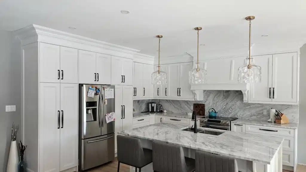 Custom kitchen cabinets in an Ontario home: floor-to-ceiling cabinet towers flanking the fridge, with a seated marble island opposite.