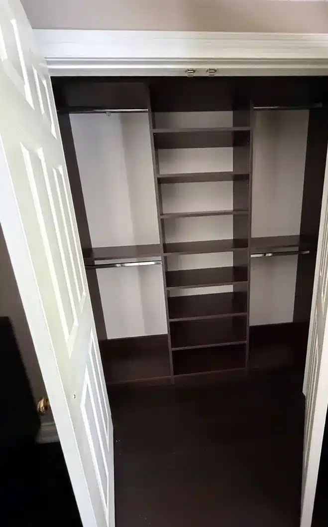Dark espresso reach-in closet in Aurora seen through open bifold doors, with a centre shelf tower and hanging rods on both sides
