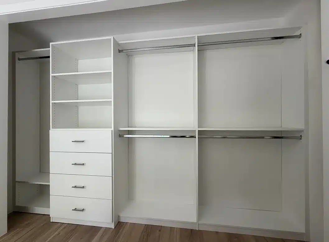 White reach-in closet with four sections: a shelf tower with drawers, double hanging in two bays and a side shelf