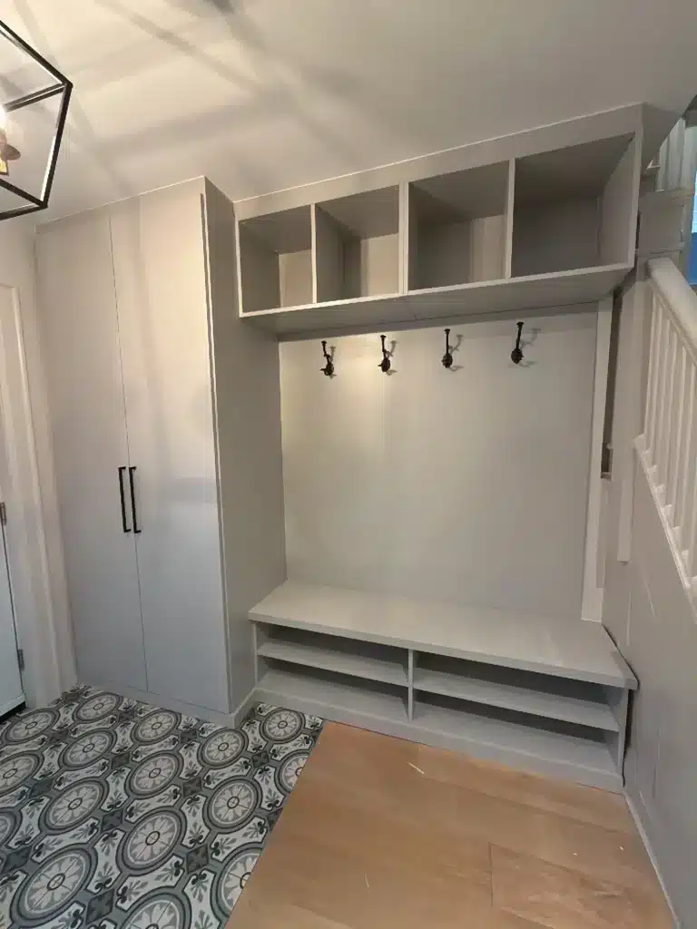 Toronto entryway with a tall two-door wardrobe, open cubbies, a row of coat hooks and a shoe bench over patterned tile