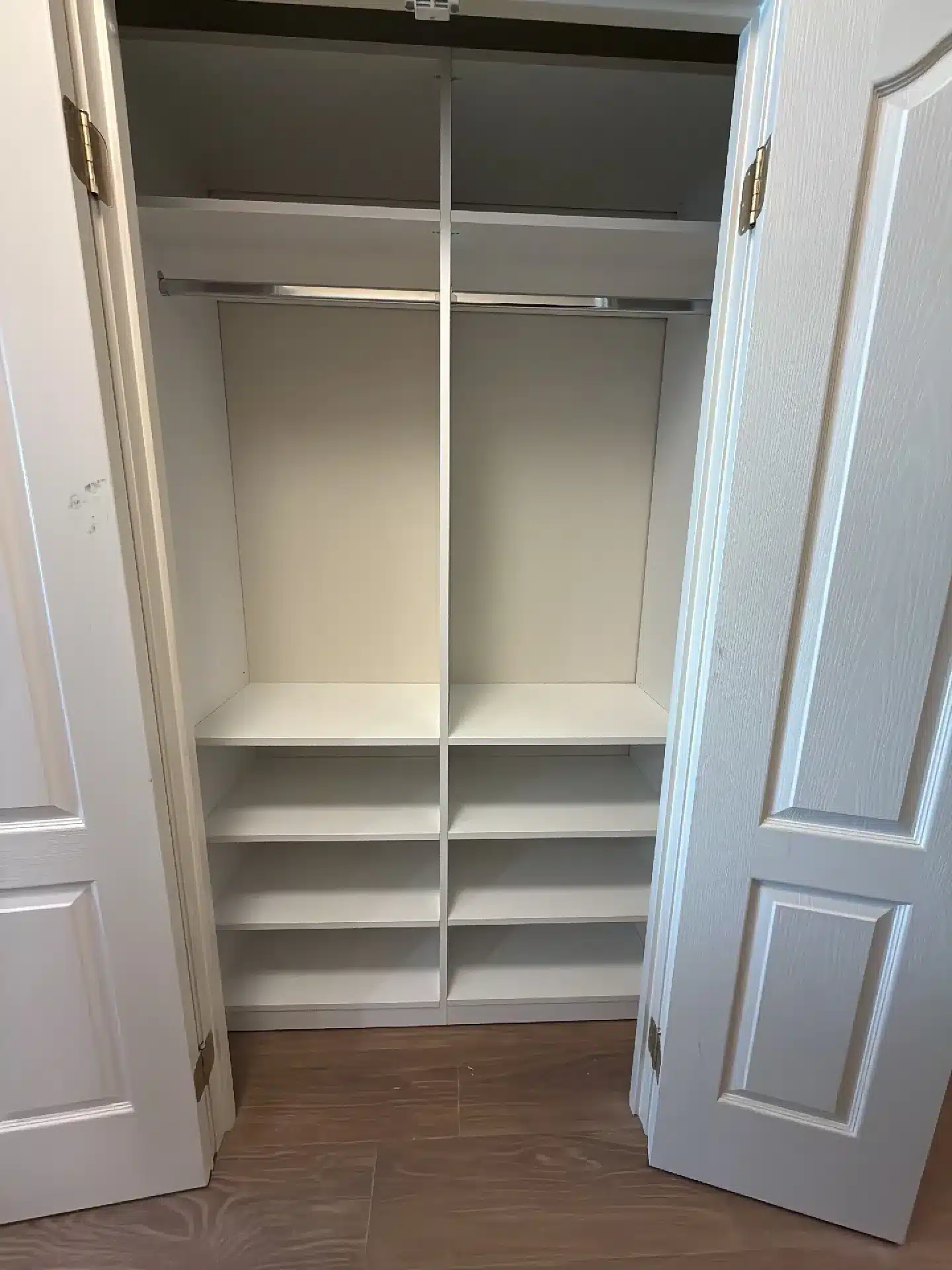 Hallway reach-in closet in Barrie with a hanging rod above two columns of shelves, bifold doors open