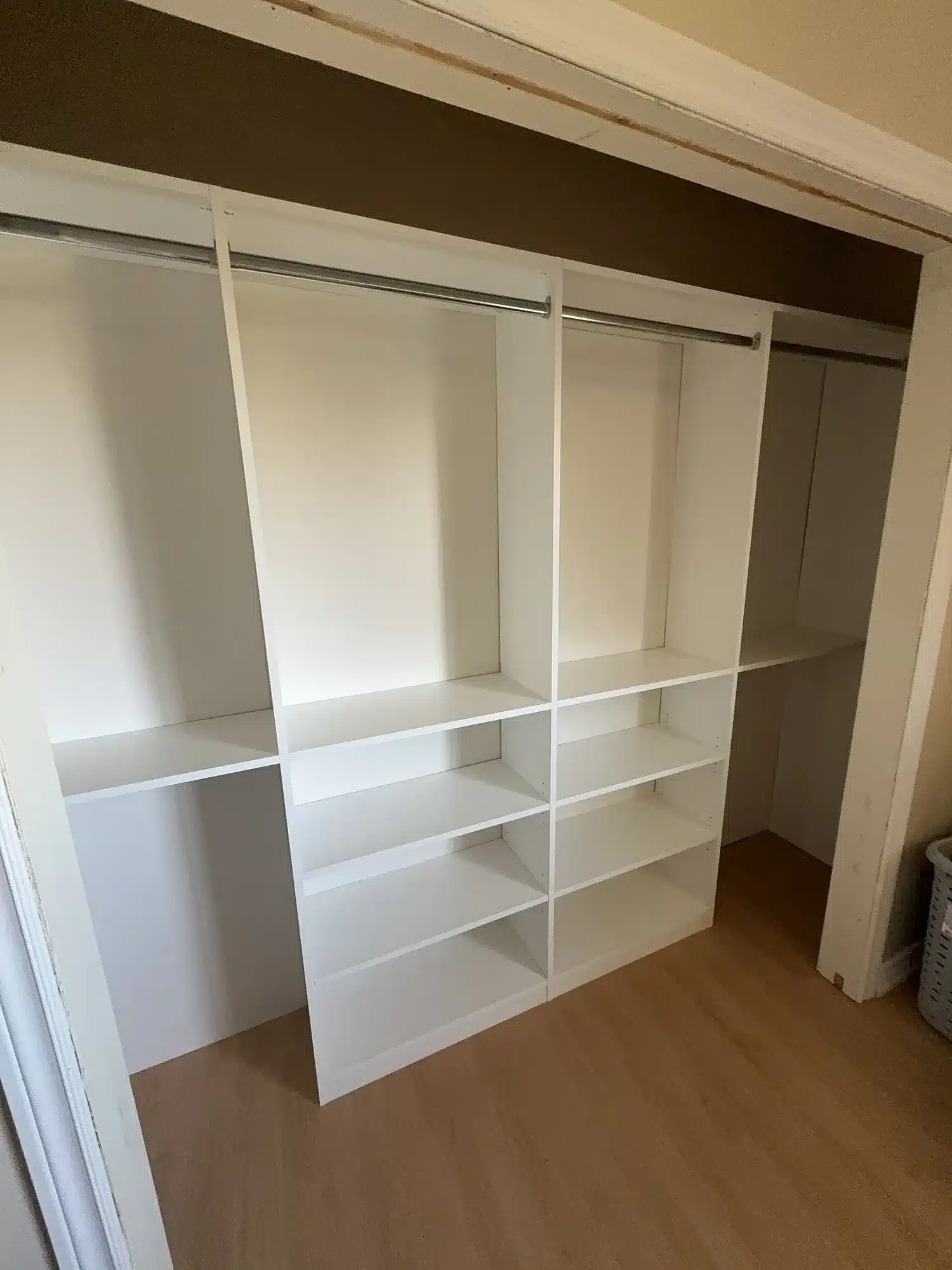 Wide reach-in closet in Oshawa with two white shelf towers between three hanging sections